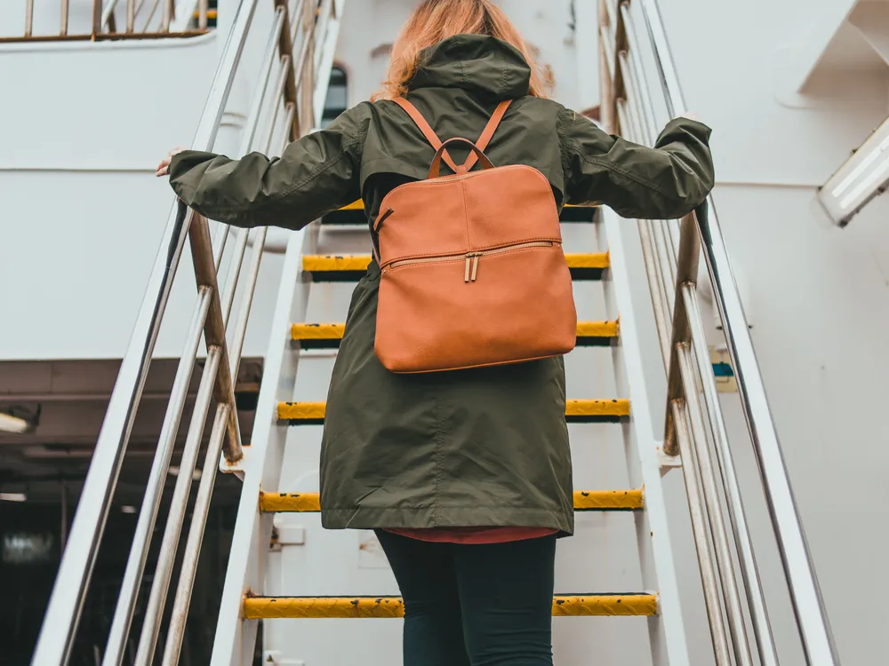 A woman with a backpack walking up a staircase, seen from behind