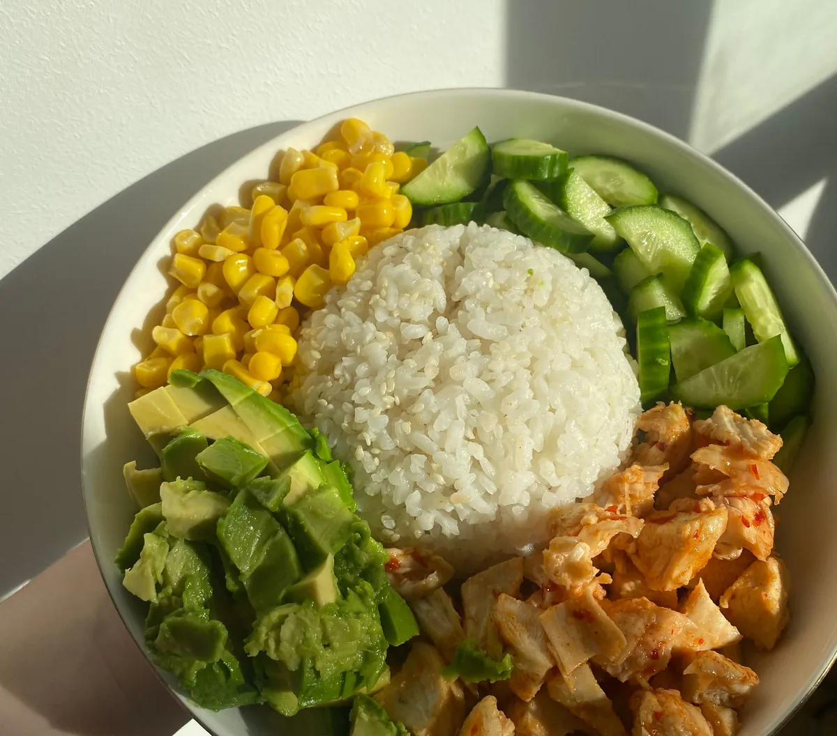ชามข้าวสวยกับไก่ ข้าวโพด แตงกวา และอะโวคาโด